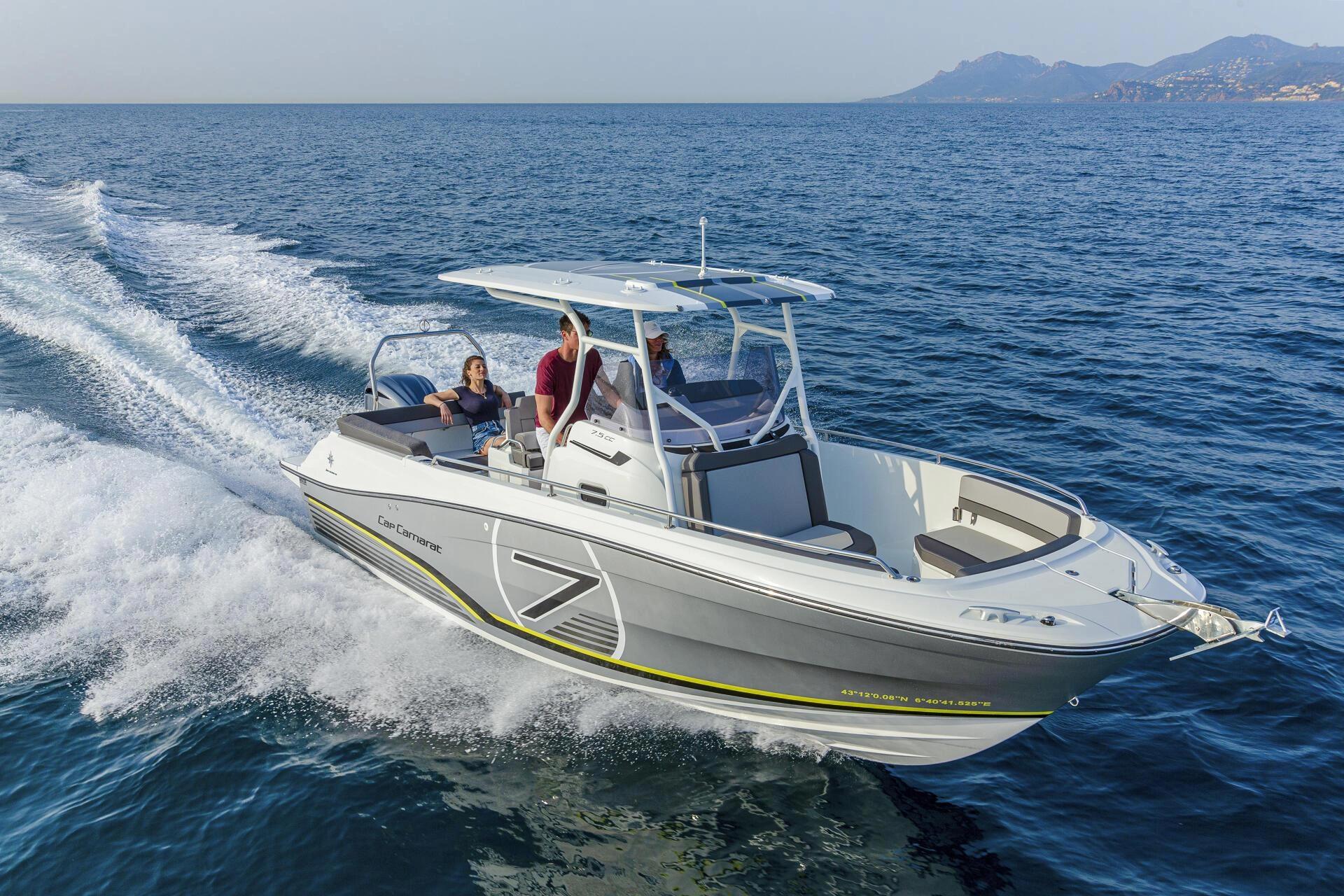 Bateau blanc navigant en Corse près des vagues avec montagnes en arrière-plan