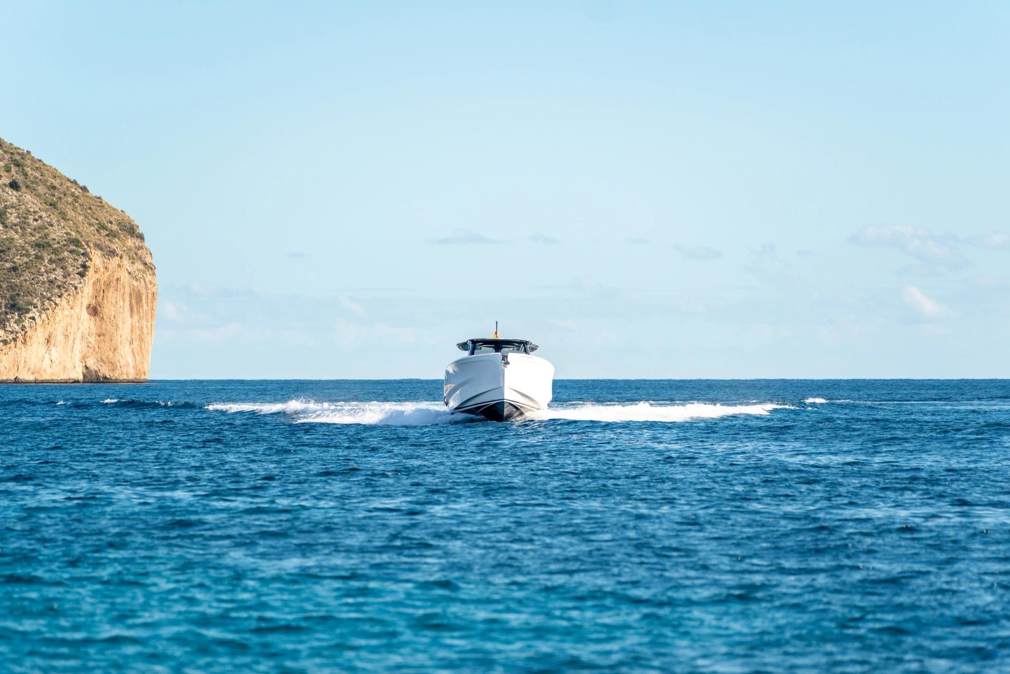Bateau blanc naviguant près d'une falaise en Corse, concessionnaire de bateaux neufs