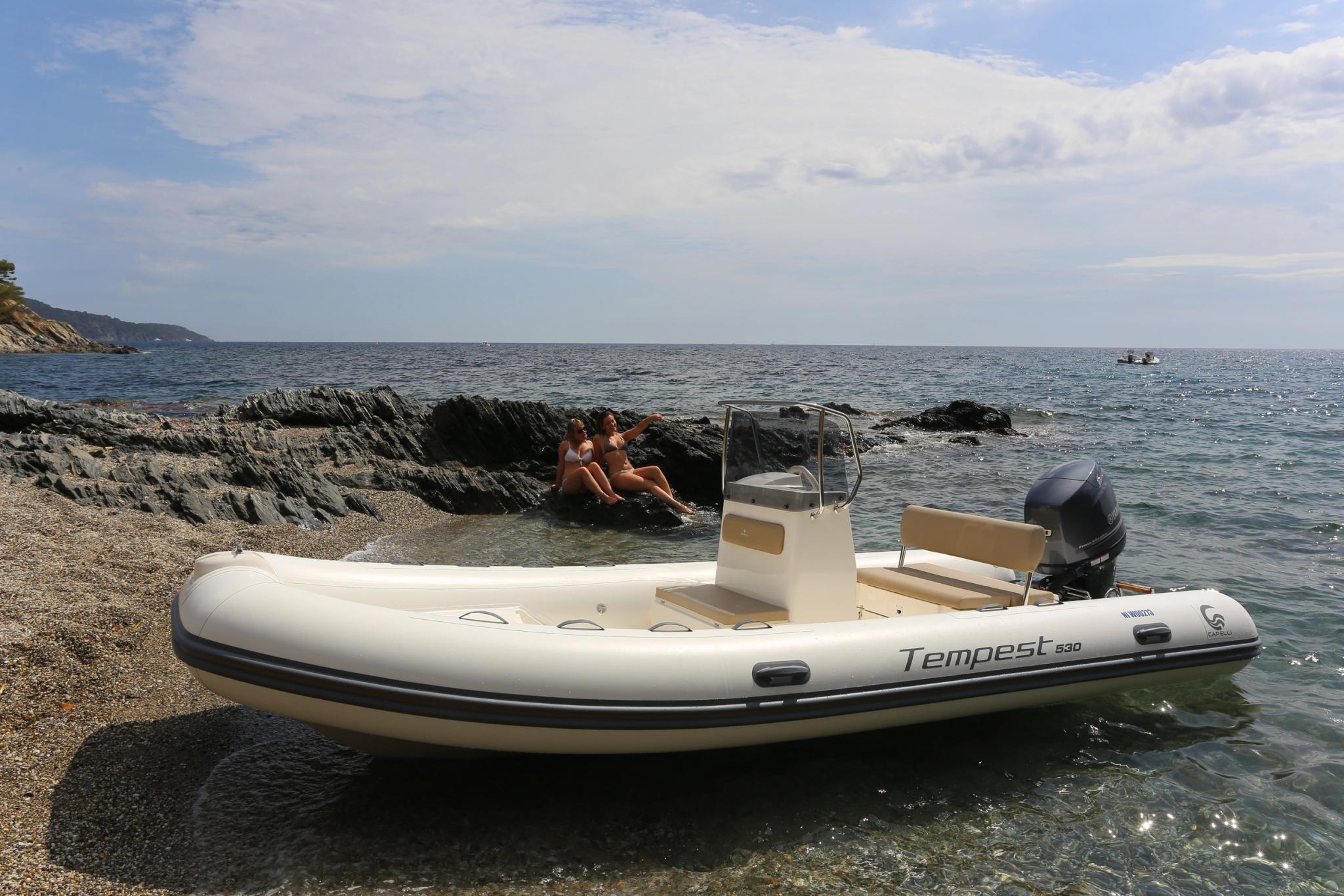 Bateau pneumatique Tempest blanc amarré sur une plage de Corse avec des rochers