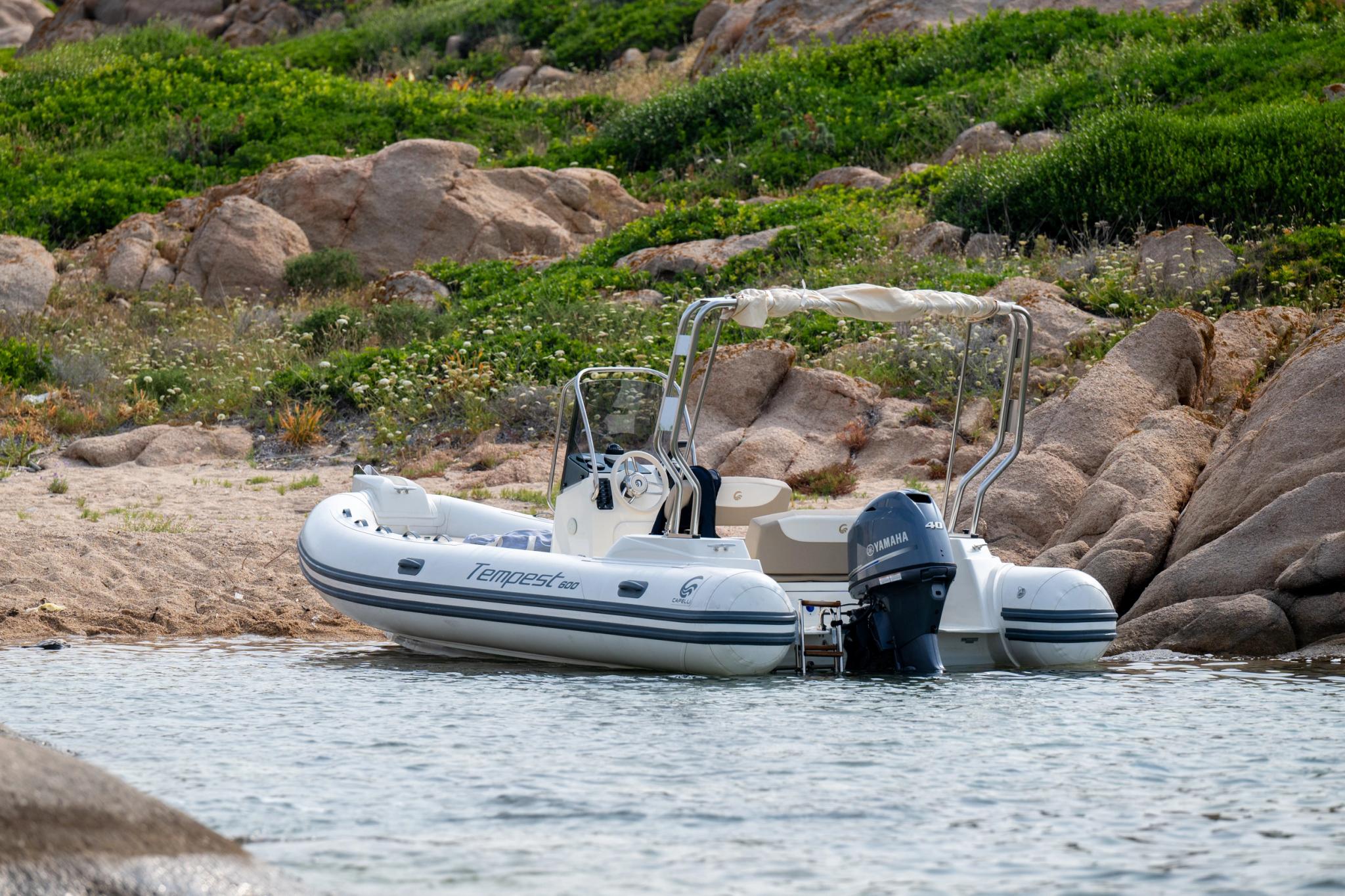 Bateau pneumatique blanc amarré en Corse près de rochers, concessionnaire de bateaux neufs