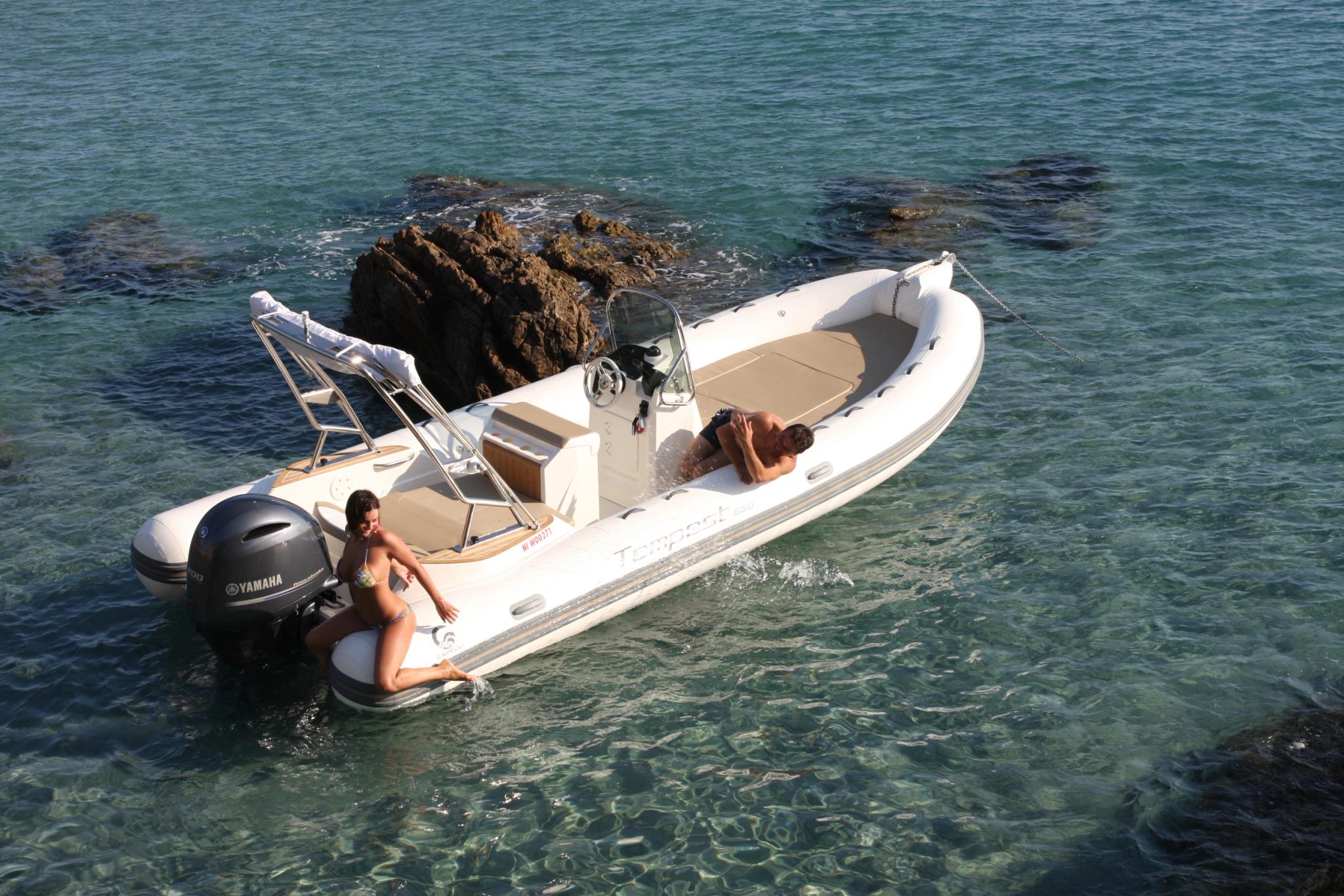 Bateau blanc neuf amarré en Corse avec deux personnes à bord près des rochers
