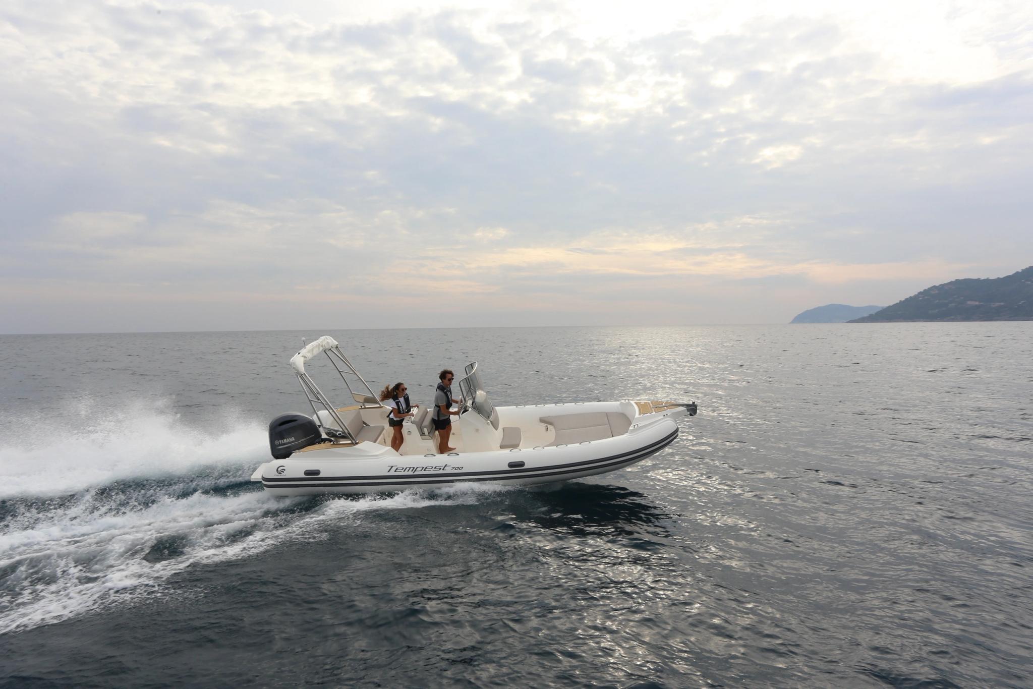 Bateau à moteur blanc avec deux personnes en mer près d'une plage de Corse