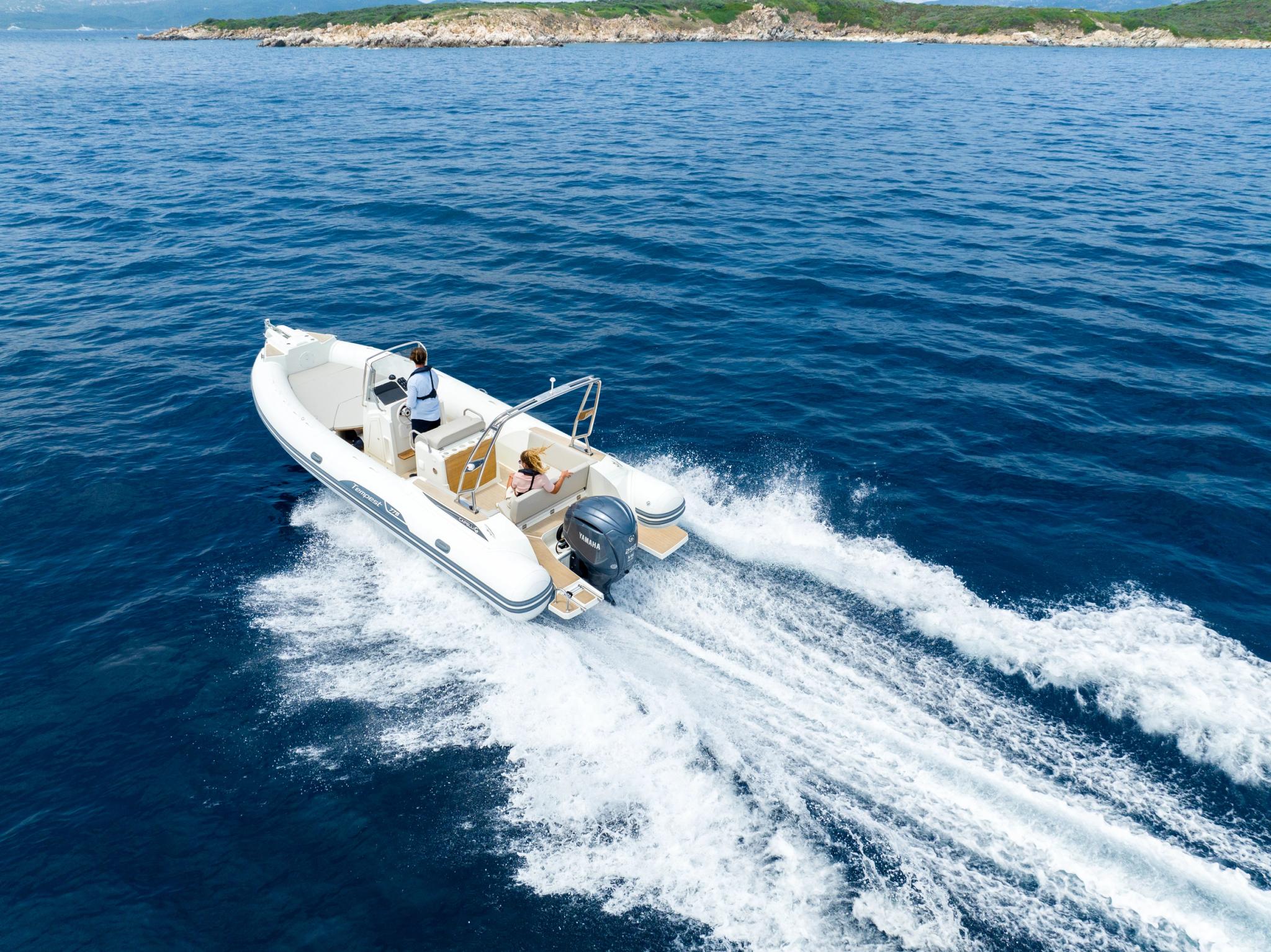 Bateau blanc de sport naviguant sur une mer bleue avec côte rocheuse en arrière-plan en Corse