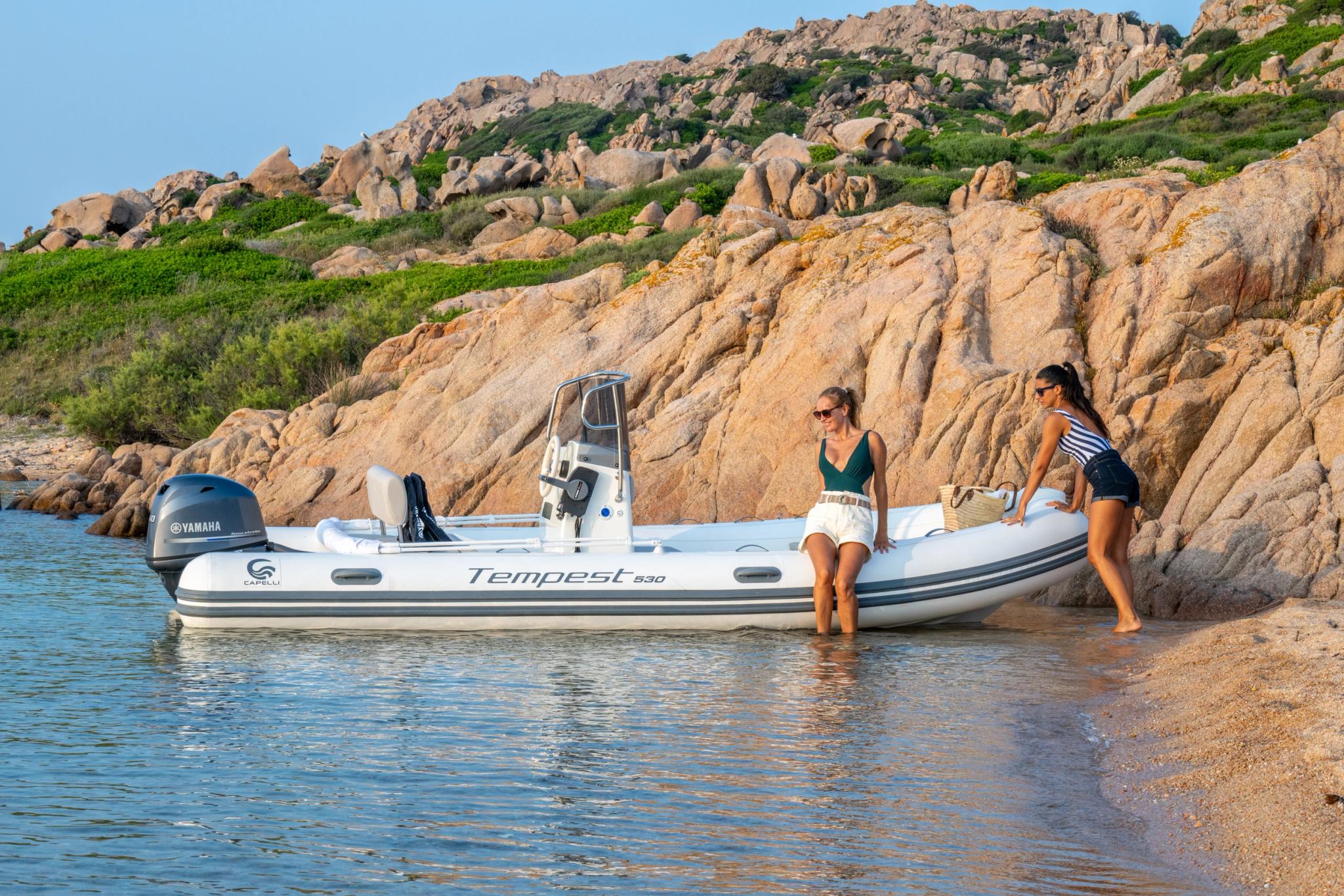 Bateau Tempest neuf amarré en Corse avec deux femmes à bord près de roches granitiques