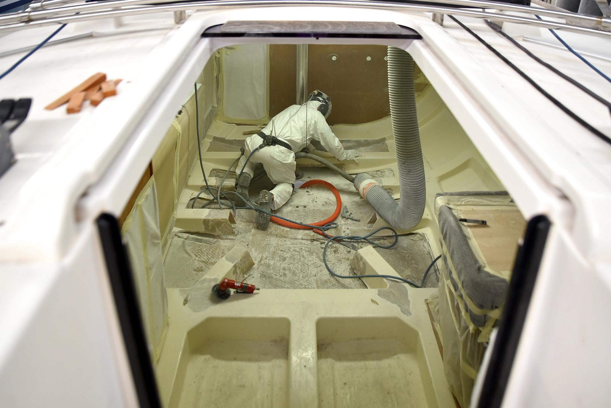 Ouvrier en combinaison blanche travaillant dans la cale d'un chantier naval