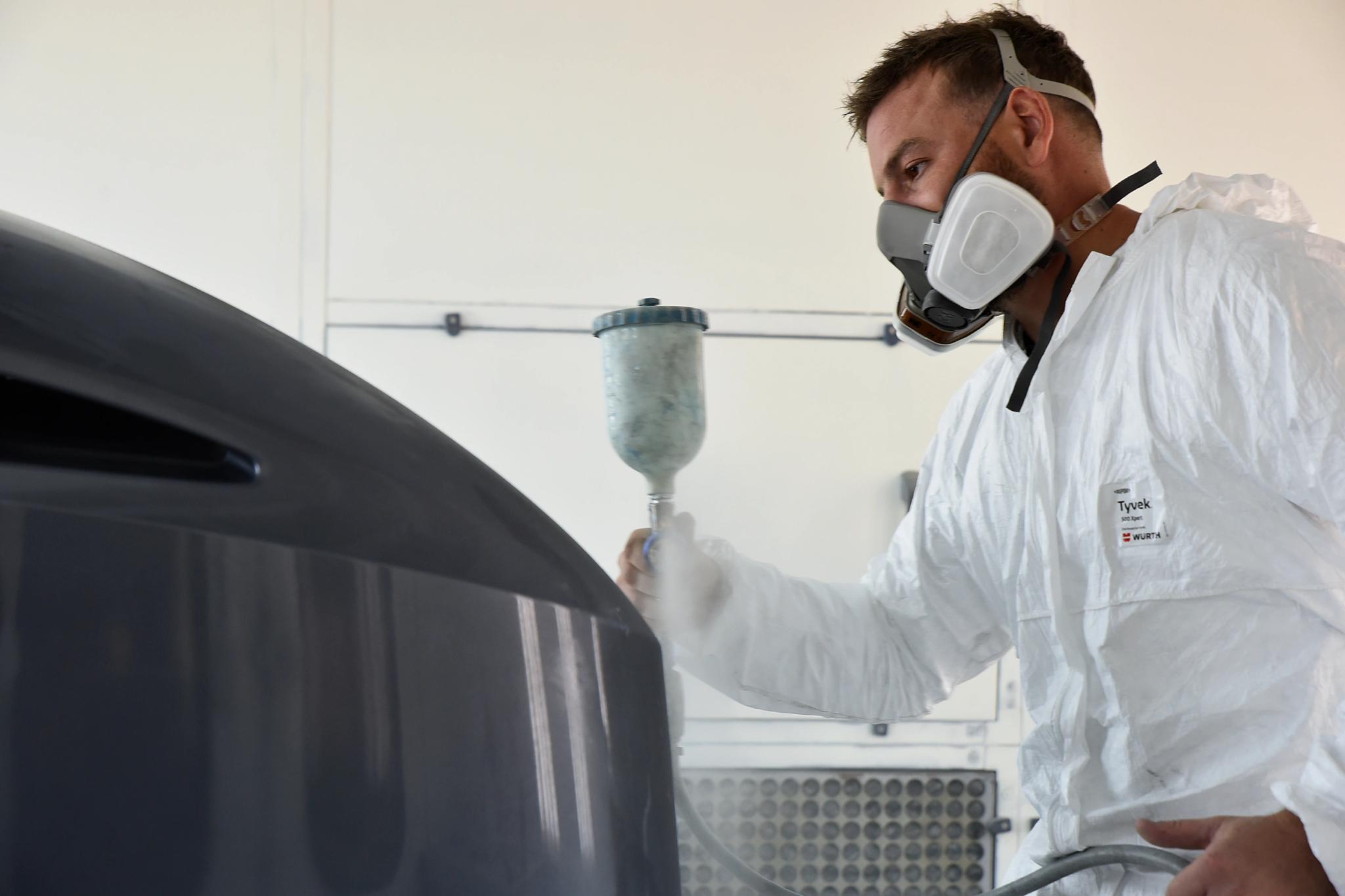 Artisan en équipement de protection pulvérisant de la peinture avec services professionnels de finition